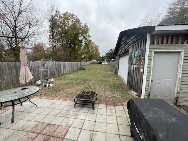 view of patio / terrace with a fire pit, a garage, and an outbuilding