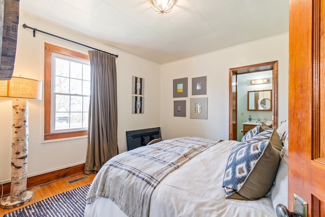 bedroom with ensuite bathroom and hardwood / wood-style floors