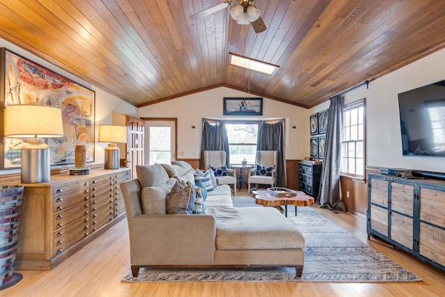 living room featuring vaulted ceiling with skylight, light hardwood / wood-style flooring, ceiling fan, and wood ceiling