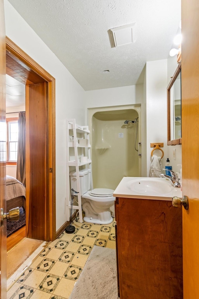 bathroom featuring a shower, vanity, a textured ceiling, and toilet