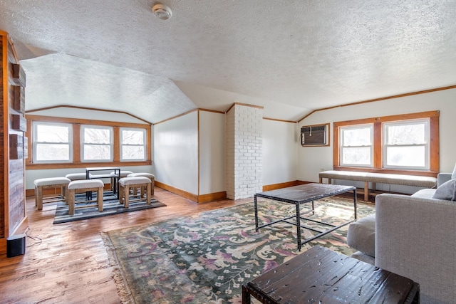 living room with hardwood / wood-style flooring, a textured ceiling, a wealth of natural light, and vaulted ceiling