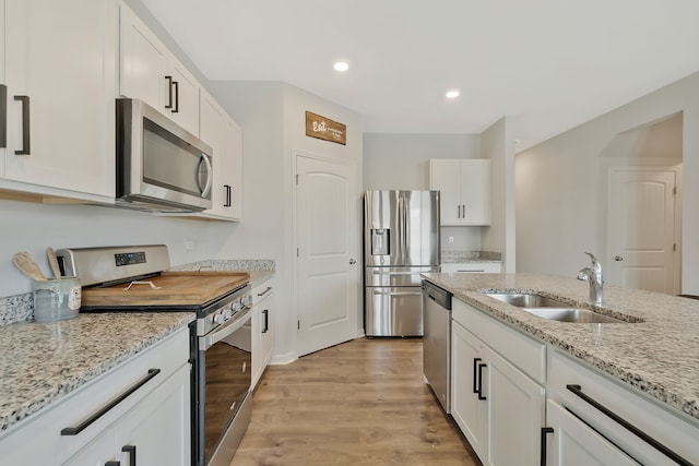 kitchen with white cabinets, sink, light hardwood / wood-style flooring, appliances with stainless steel finishes, and light stone counters