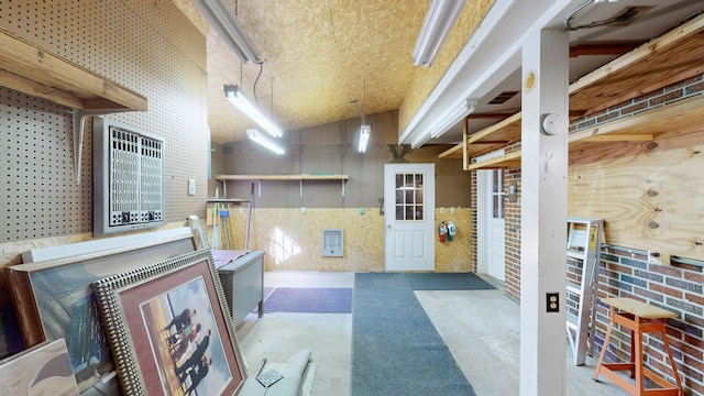 misc room with brick wall, high vaulted ceiling, and concrete floors