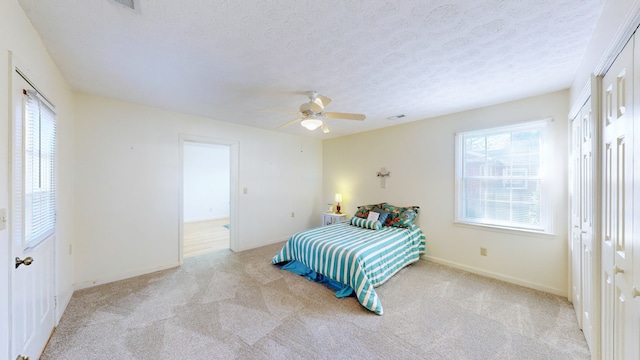 carpeted bedroom featuring a textured ceiling, two closets, and ceiling fan