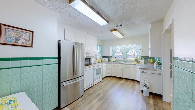 kitchen with tile walls, white cabinets, white appliances, and light wood-type flooring