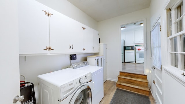 laundry area featuring cabinets, light hardwood / wood-style floors, and washing machine and clothes dryer