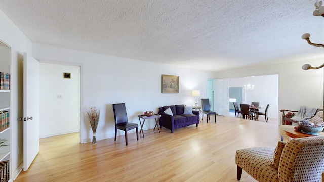 sitting room featuring a notable chandelier, light hardwood / wood-style floors, and a textured ceiling