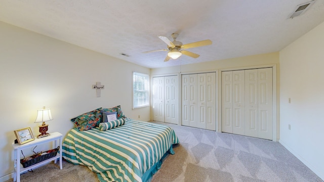 bedroom featuring carpet floors, ceiling fan, and multiple closets