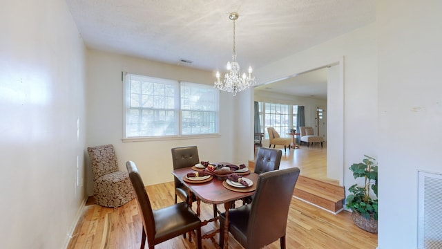 dining space featuring a textured ceiling, an inviting chandelier, and light hardwood / wood-style flooring