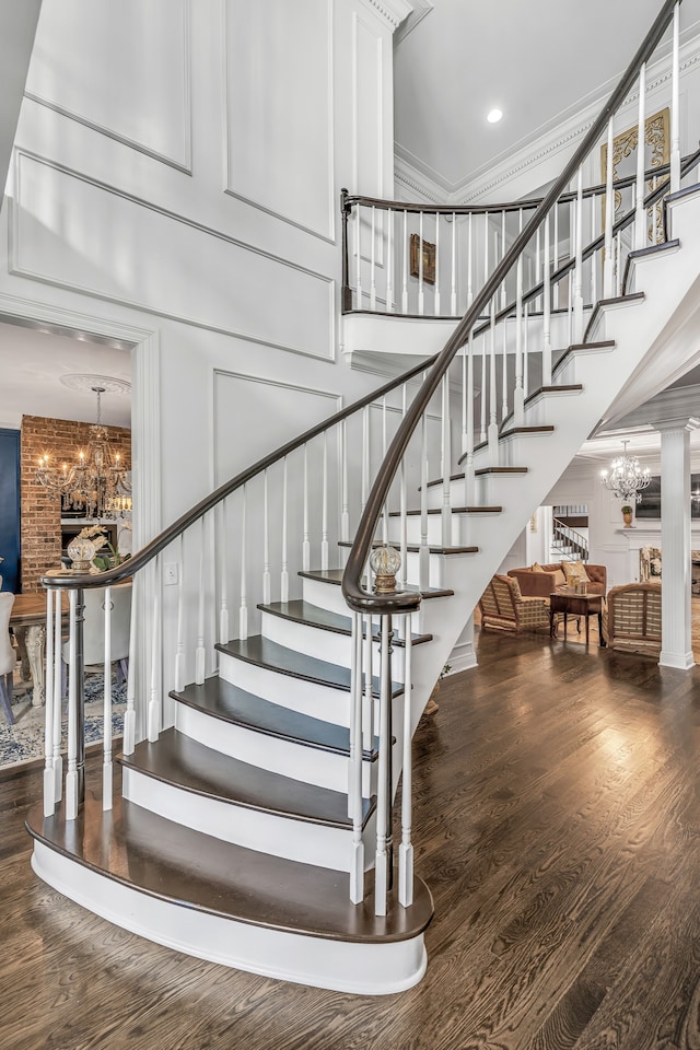 stairs with an inviting chandelier, hardwood / wood-style flooring, and a towering ceiling