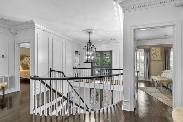 corridor with ornamental molding, an inviting chandelier, and dark hardwood / wood-style flooring