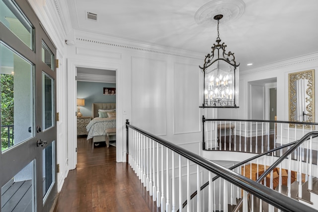 hall with an inviting chandelier, ornamental molding, and dark hardwood / wood-style floors