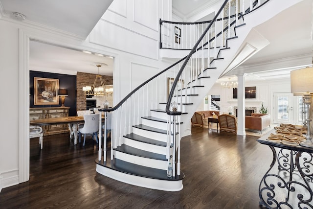 stairs with crown molding, wood finished floors, and a fireplace