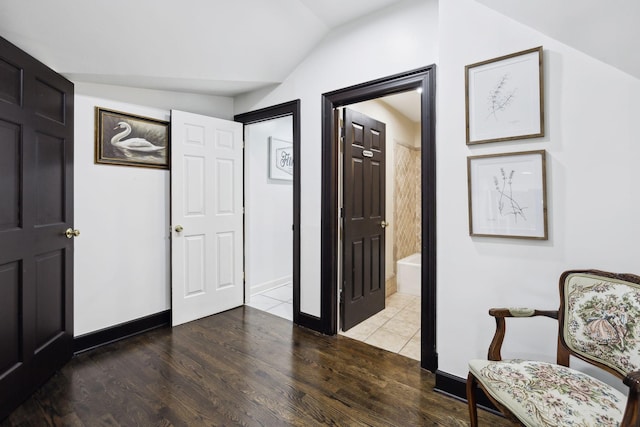 interior space with baseboards, wood finished floors, and vaulted ceiling