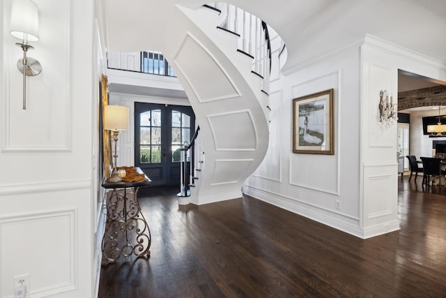 foyer entrance with dark wood-type flooring, a healthy amount of sunlight, stairs, and a decorative wall