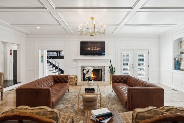 living room featuring coffered ceiling, a chandelier, crown molding, and a decorative wall