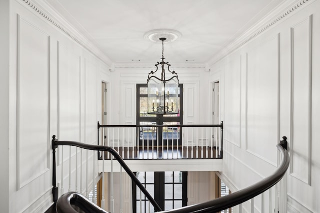 hall featuring an upstairs landing, a notable chandelier, ornamental molding, and a decorative wall