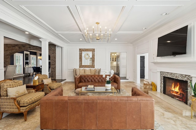 living room featuring ornamental molding, coffered ceiling, a decorative wall, a premium fireplace, and ornate columns