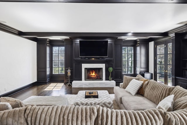 living area with a wealth of natural light, a premium fireplace, dark wood-type flooring, and ornamental molding