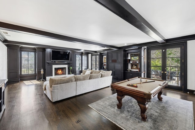 rec room with pool table, beam ceiling, dark wood-style flooring, and a warm lit fireplace