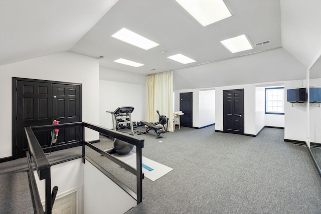 exercise room with visible vents, carpet floors, baseboards, and vaulted ceiling