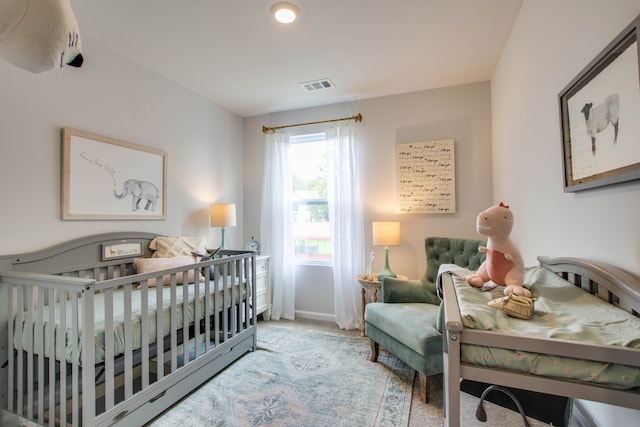 bedroom featuring light colored carpet and a nursery area