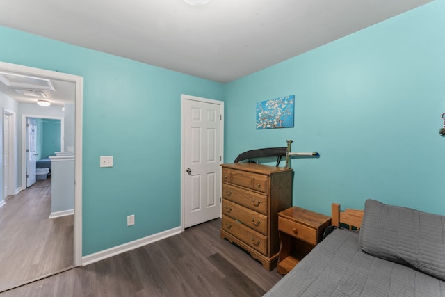 bedroom featuring ensuite bath and dark hardwood / wood-style floors