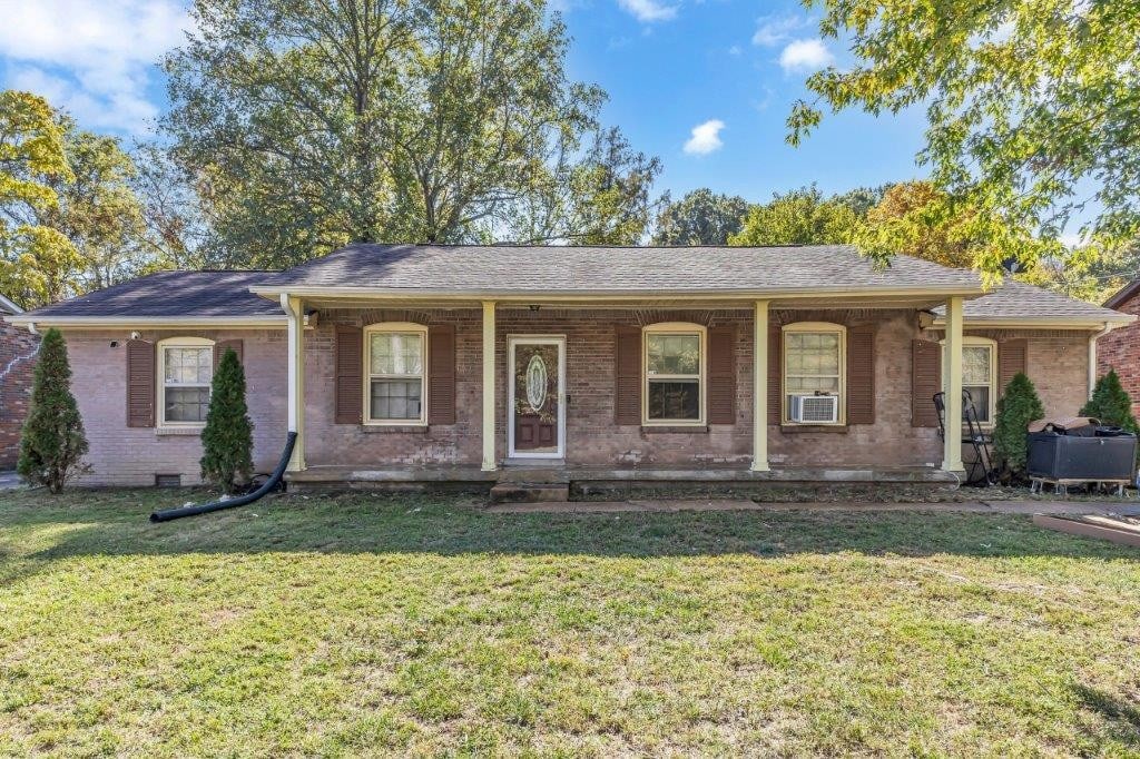 ranch-style home featuring cooling unit and a front lawn