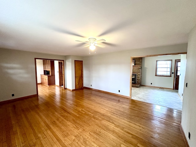 unfurnished room featuring ceiling fan, light hardwood / wood-style floors, and a brick fireplace