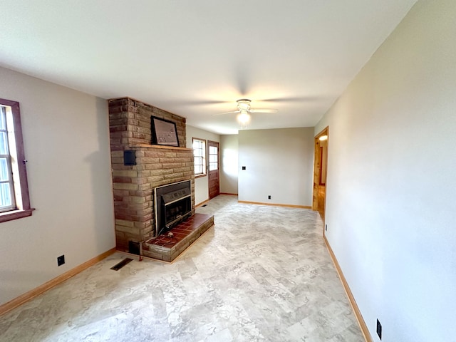 unfurnished living room with ceiling fan and a brick fireplace