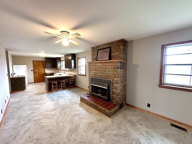 unfurnished living room featuring a brick fireplace and ceiling fan