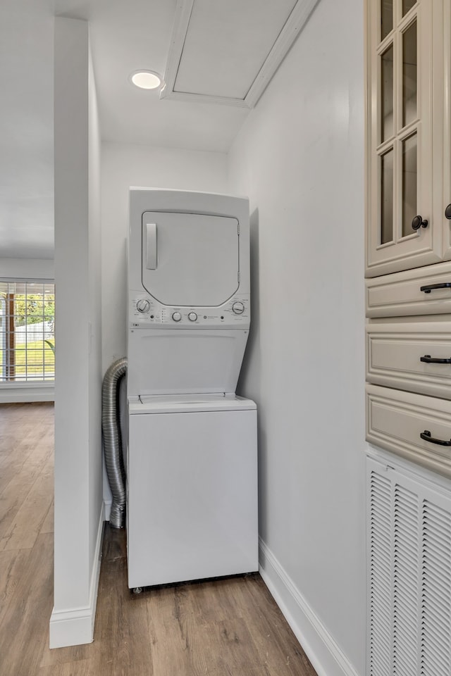 laundry area featuring stacked washer and dryer and hardwood / wood-style flooring