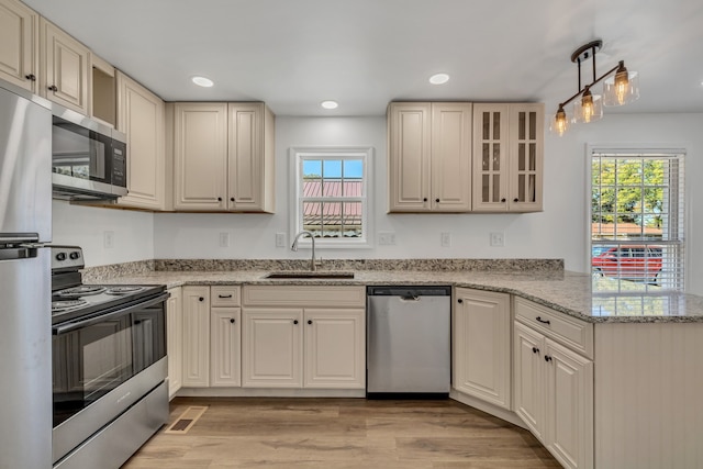 kitchen featuring a wealth of natural light, sink, stainless steel appliances, and light wood-type flooring