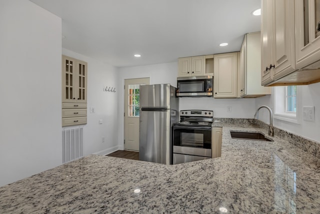 kitchen with light stone countertops, sink, stainless steel appliances, dark hardwood / wood-style flooring, and cream cabinetry