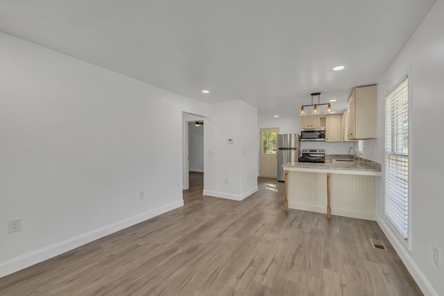 kitchen featuring light hardwood / wood-style flooring, ceiling fan, appliances with stainless steel finishes, decorative light fixtures, and kitchen peninsula