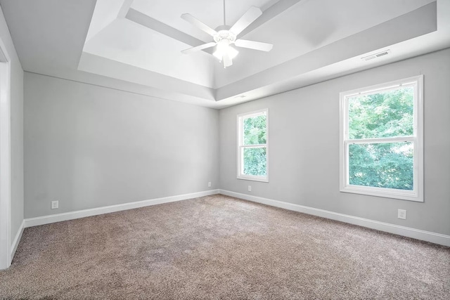 carpeted spare room featuring a raised ceiling and ceiling fan