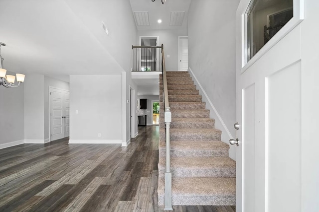 stairway featuring wood-type flooring, an inviting chandelier, and a high ceiling