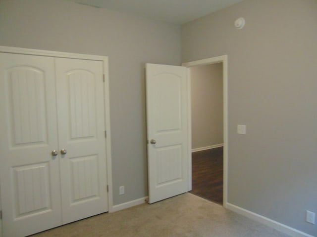 unfurnished bedroom with light carpet and a closet