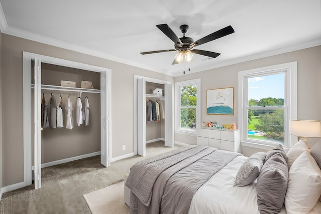 bedroom featuring multiple windows, crown molding, ceiling fan, and multiple closets