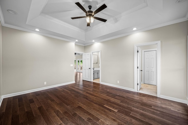 spare room featuring a raised ceiling, ceiling fan, dark hardwood / wood-style floors, and ornamental molding