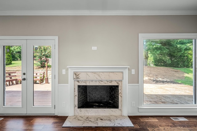 unfurnished living room featuring crown molding, dark hardwood / wood-style flooring, a fireplace, and french doors