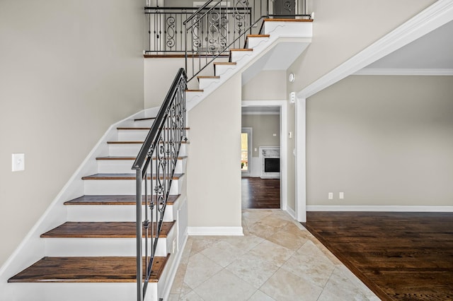 stairs with tile patterned floors, ornamental molding, and a high ceiling