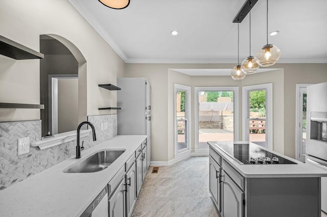 kitchen with decorative backsplash, black electric stovetop, ornamental molding, sink, and decorative light fixtures