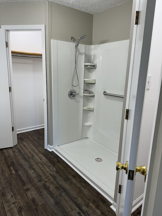 bathroom with hardwood / wood-style floors, a textured ceiling, and walk in shower