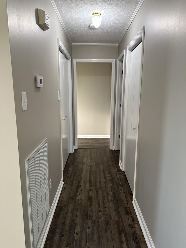 hall featuring a textured ceiling, crown molding, and dark wood-type flooring