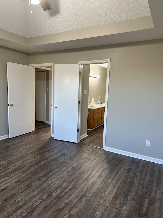 unfurnished bedroom featuring a textured ceiling, ceiling fan, dark hardwood / wood-style floors, and ensuite bathroom