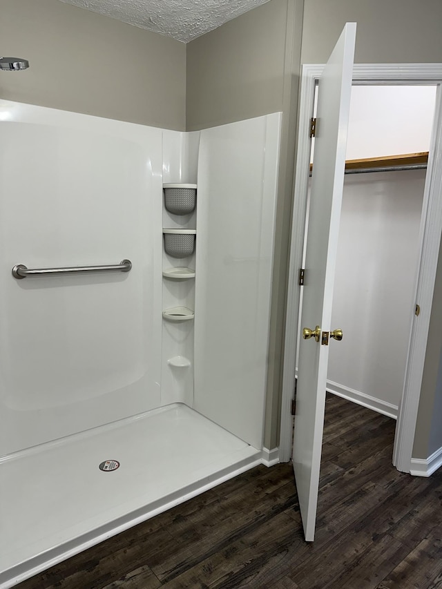 bathroom with wood-type flooring, a textured ceiling, and walk in shower