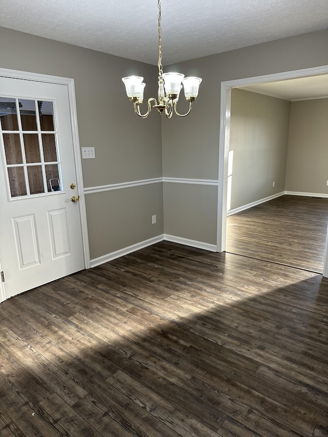 unfurnished dining area with dark hardwood / wood-style flooring, a textured ceiling, and a chandelier