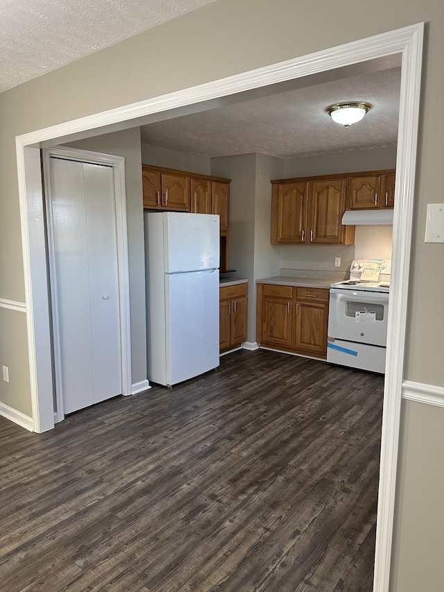 kitchen featuring dark hardwood / wood-style floors, white appliances, and a textured ceiling