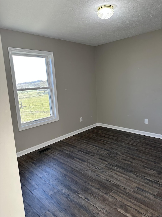 empty room featuring a textured ceiling and dark hardwood / wood-style floors